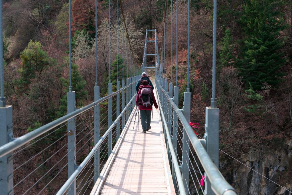 People Walking on Narrow Steel and Wooden Bridge over