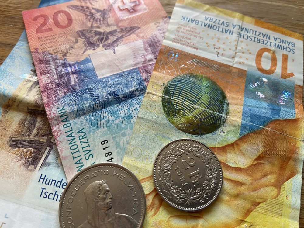 Close-up of Swiss banknotes and coins in various denominations, showcasing the colorful currency of Switzerland.