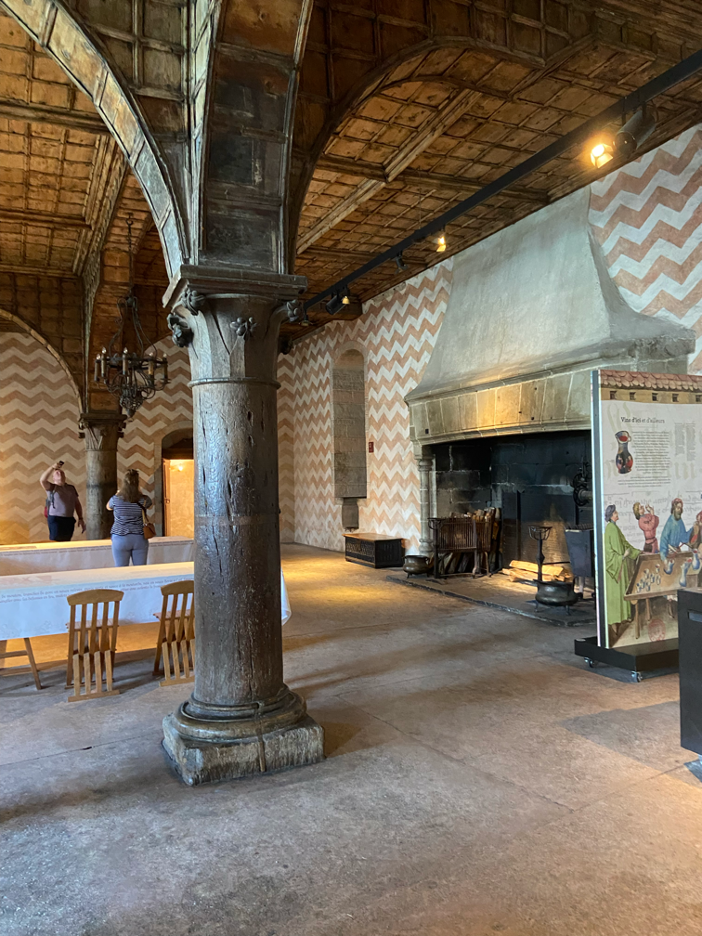 A historic room inside Chillon Castle Montreux, featuring a large medieval fireplace and a vaulted column, showcasing the castle's architectural elegance and historical charm.