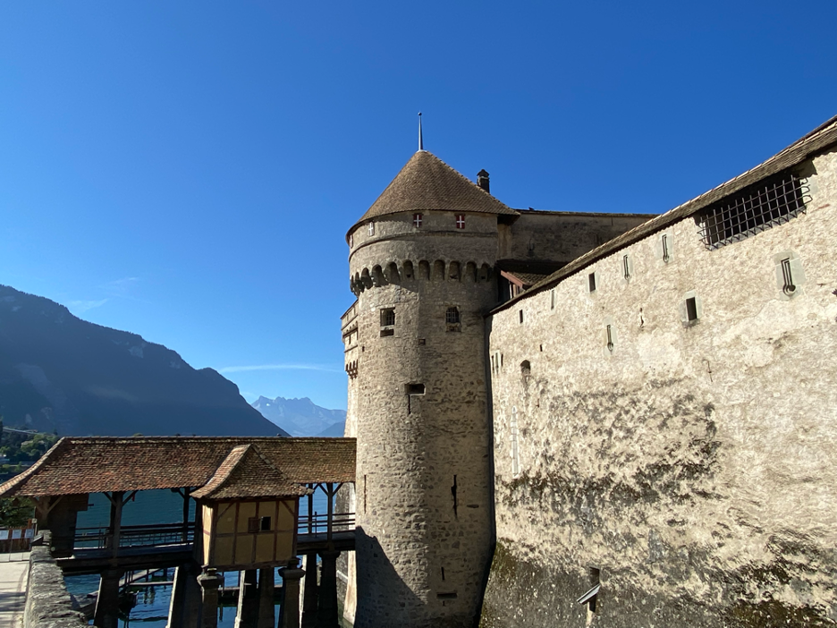 Bridge leading over the water into Chillon Castle, with its iconic tower standing tall above Lake Geneva.