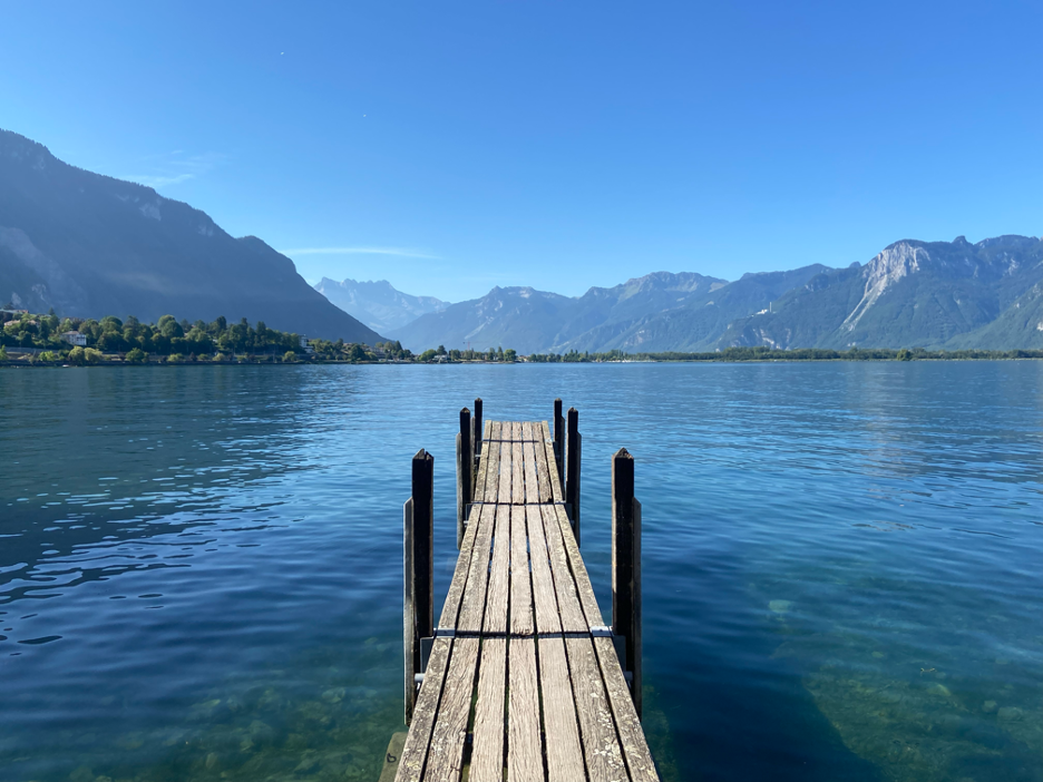 A small wooden pier extending into Lake Geneva near Chillon Castle, offering stunning lake views.