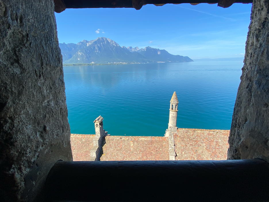 Stunning view from Chillon Castle onto the distant mountains, framed by the blue waters of Lake Geneva.