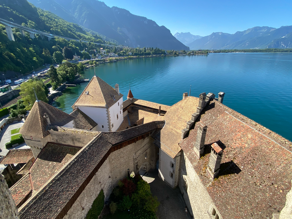 A picturesque view of Chillon Castle's courtyard, rooftops, and the tranquil lake beyond.