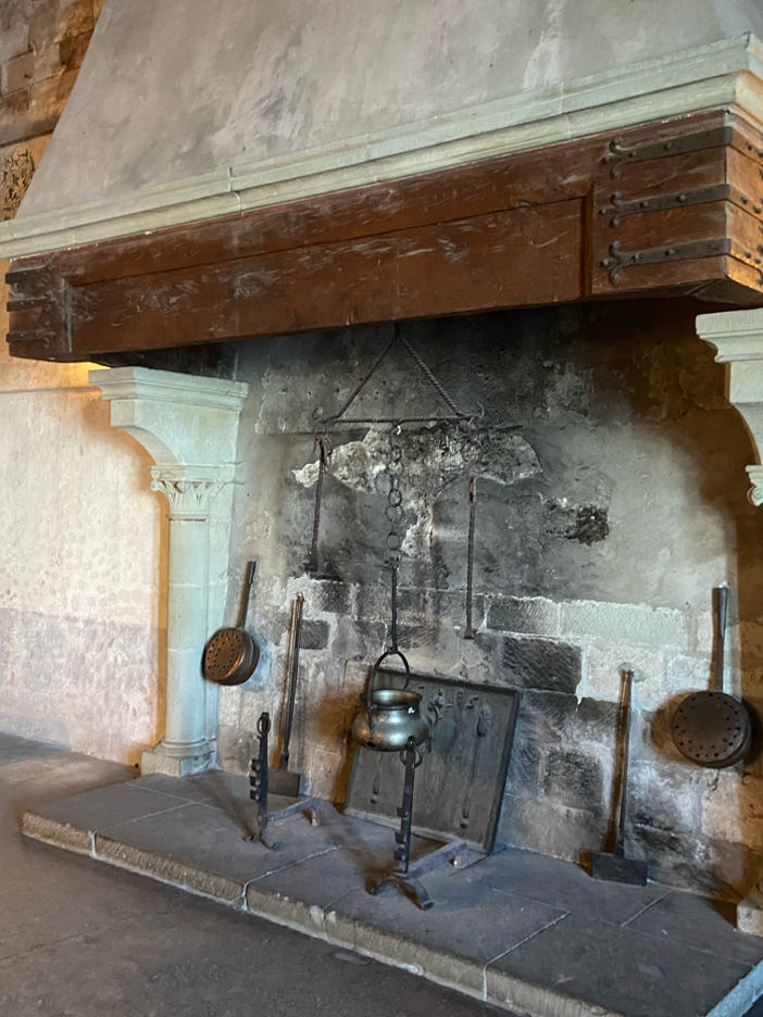 Inside Chillon Castle Montreux, a large medieval fireplace adds warmth to the historic stone interior.