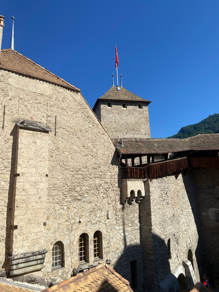 An aerial perspective of Chillon Castle’s courtyard, with a tower and wooden walkways.