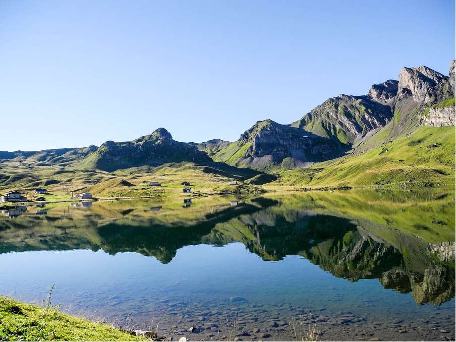 A serene alpine lake near the car-free mountain resort of Melchsee-Frutt, reflecting the surrounding peaks and pristine beauty of the Swiss Alps.