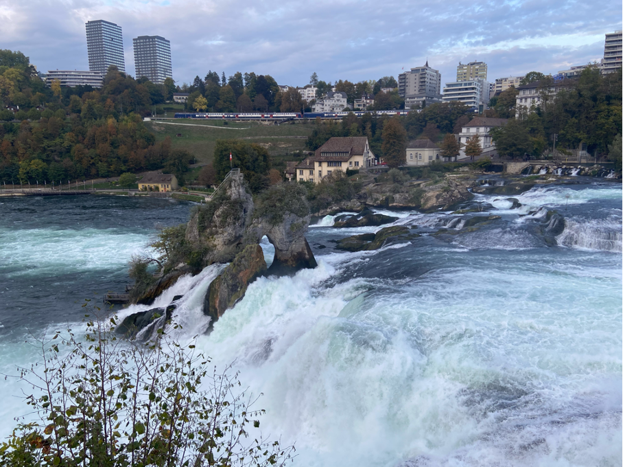 View of Rhine Falls from Laufen on a cloudy day, with cascading water creating a breathtaking scene. A day trip from Zurich to Rhine Falls lets you experience this natural wonder up close, complete with the sight and sound of the powerful falls.