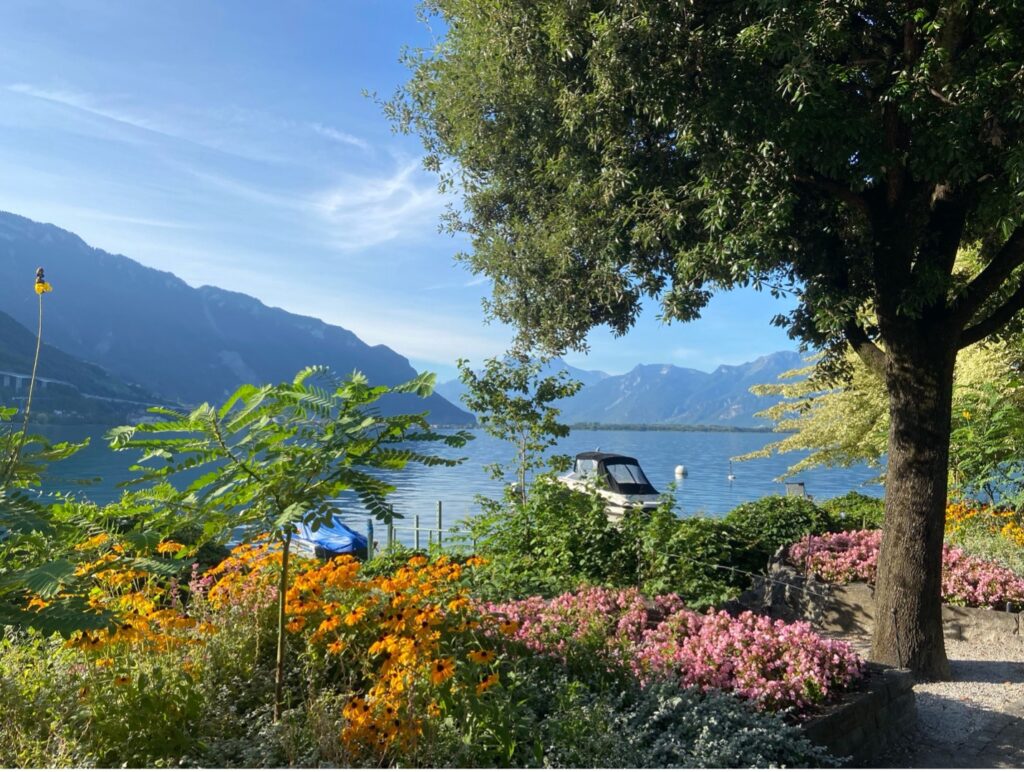 A peaceful view of the flower-lined lakeside promenade in Montreux, with the serene waters of Lake Geneva.