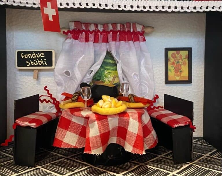 Handcrafted model of a cozy chalet dining room serving traditional Swiss fondue, capturing the warm ambiance of the best fondue in Zurich.
