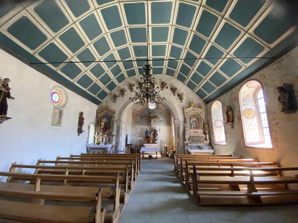 Interior of Büelkirche Chapel in Weesen with altar, wooden benches and statues.