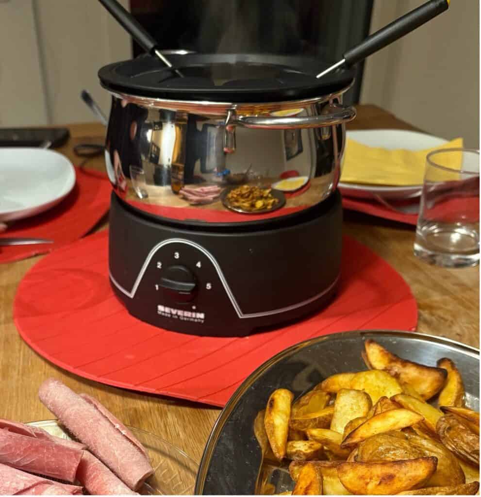 Swiss meat fondue pot with simmering broth and fries served on the side.
