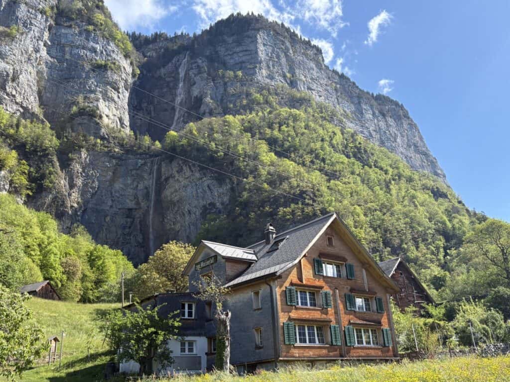 View of Seerenbach Falls and traditional chalet type house from Betlis Chapel near Lake Walensee