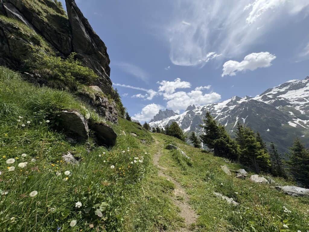 Hiking along the Grotzli Trail past green alpine meadows with panoramic mountain views