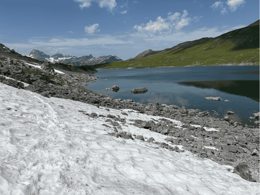 Hiking trail leading to a leftover snowfield in June at Glattalpsee, Swiss mountain lake