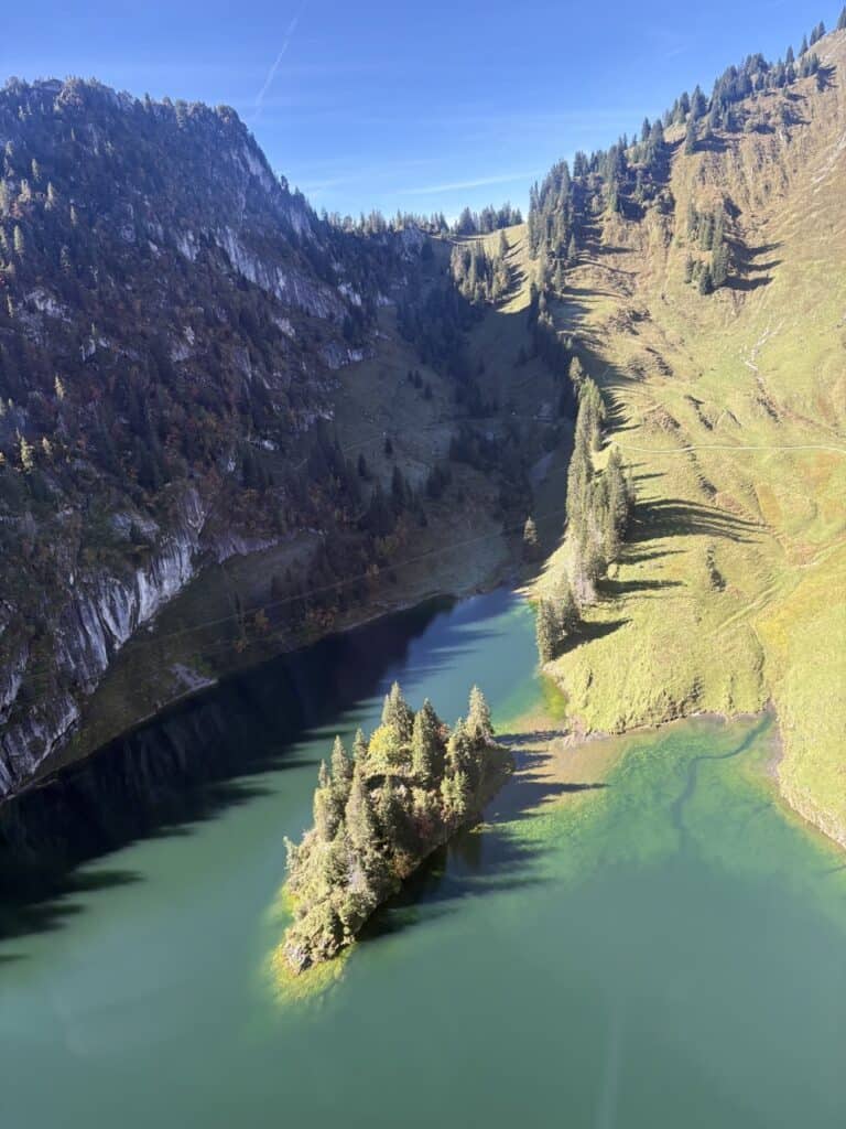 Aerial view from the cable car down to the emerald-green Hinterstockensee, a beautiful mountain lake in Switzerland.
