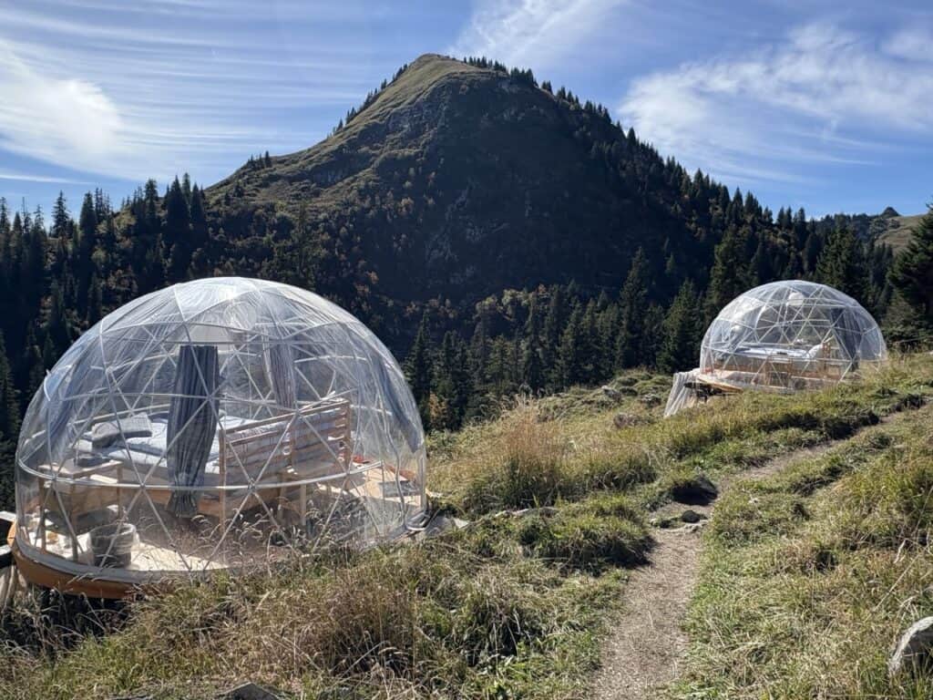 Garden igloos with star beds set up near the Berggasthaus Oberstockenalp, featuring cozy transparent domes in a scenic alpine garden.