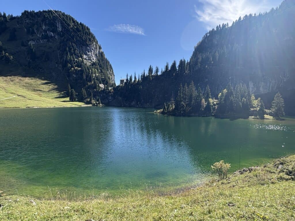 Emerald-green Hinterstockensee, a serene mountain lake surrounded by alpine landscape.
