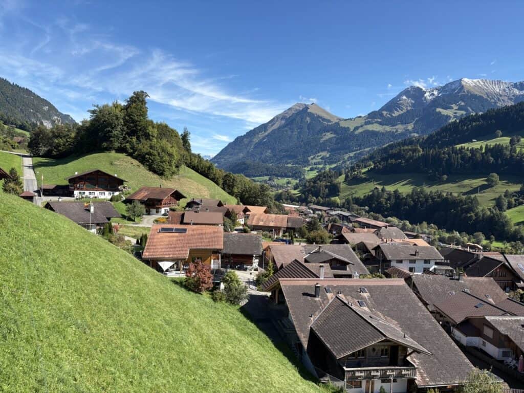 View from the Stockhorn cable car overlooking the village of Erlenbach with traditional Swiss chalets, green pastures, and mountains in the Simmental Valley.
