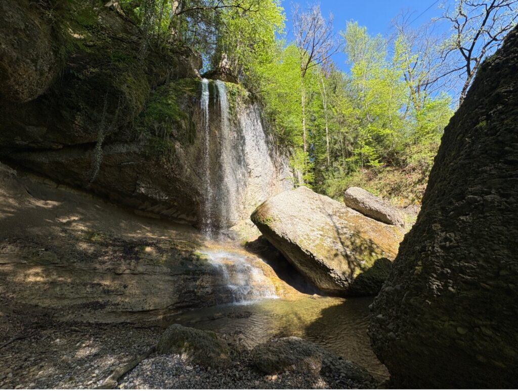 Äulischlucht waterfall near Zurich on a sunny spring day, flowing between rocks.
