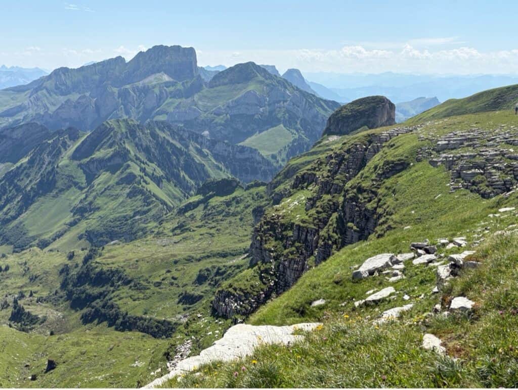 Walking along the Rosenboden Plateau circular trail on Chäserrugg with views of rugged green alpine peaks.