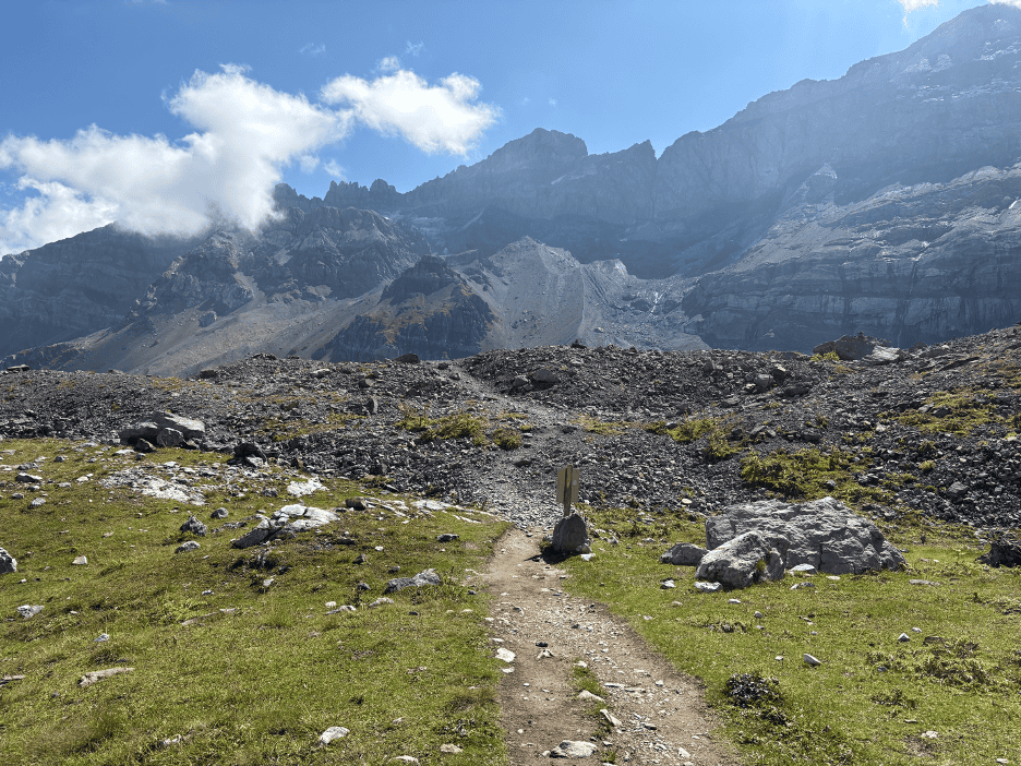 Hiking trail to Gletscherseeli at Klausenpass, showing the landscape transition from green alpine meadows to rocky terrain, part of one of the best short hikes in Switzerland.
