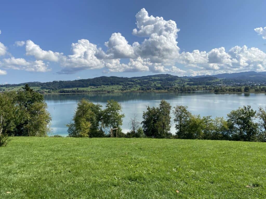Lake Pfäffikon with its shimmering waters surrounded by hilly green landscape. 