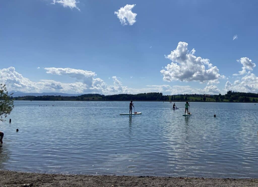 Stand-up paddleboarders on Lake Pfäffikon enjoying calm waters and scenic views close to Zurich. 