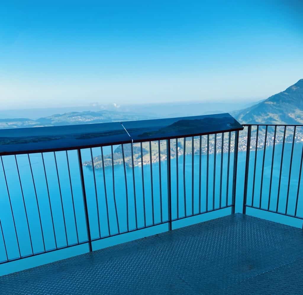 View from Hammetschwand station over Lake Lucerne with mountain information boards along the railing.