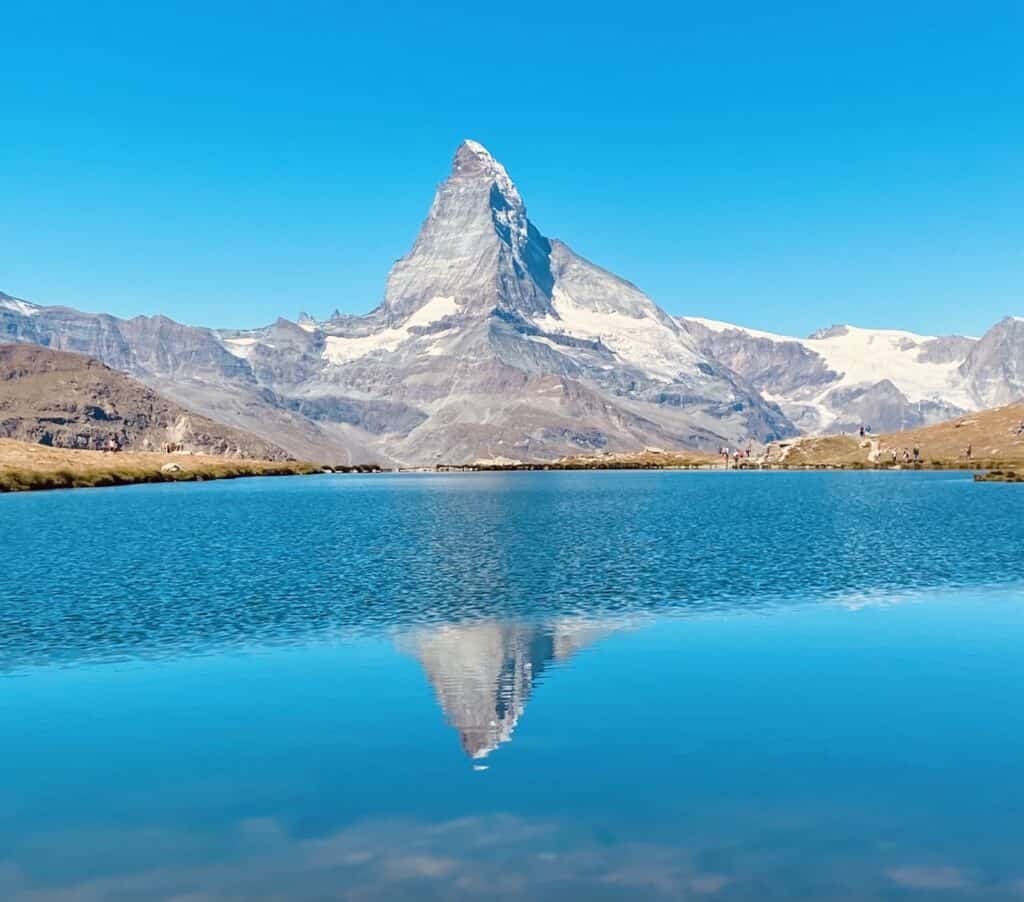 Stellisee above Zermatt reflecting the Matterhorn on a sunny day in the Swiss Alps.
