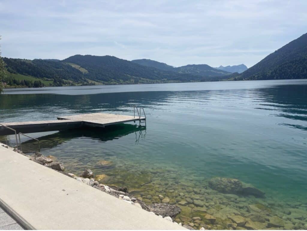 Breiten bathing area at Lake Aegeri with stone seating steps, dock with easy water access and turquoise lake views.