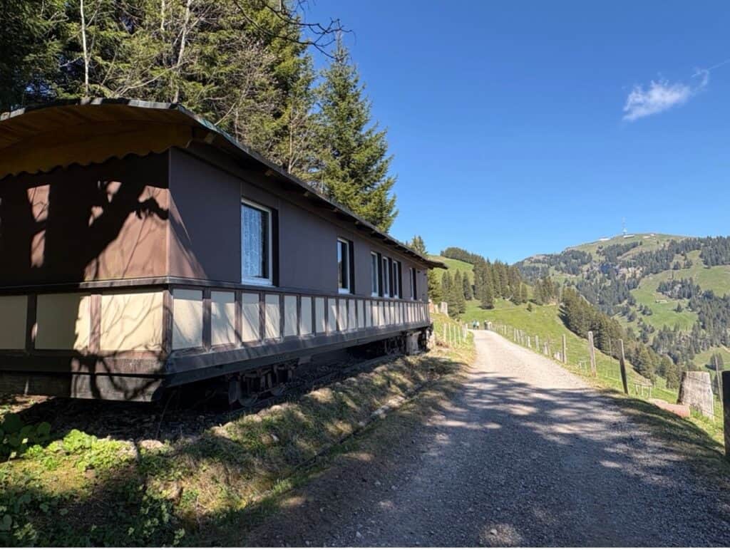 Retired railway passenger carriage standing beside the hiking trail on Mount Rigi
