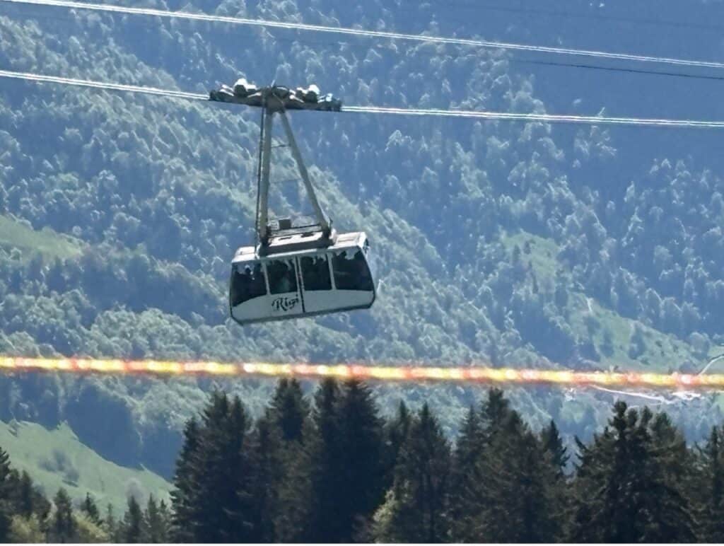 Cable car traveling between Rigi Kaltbad and Weggis with wooded landscape in the background. 