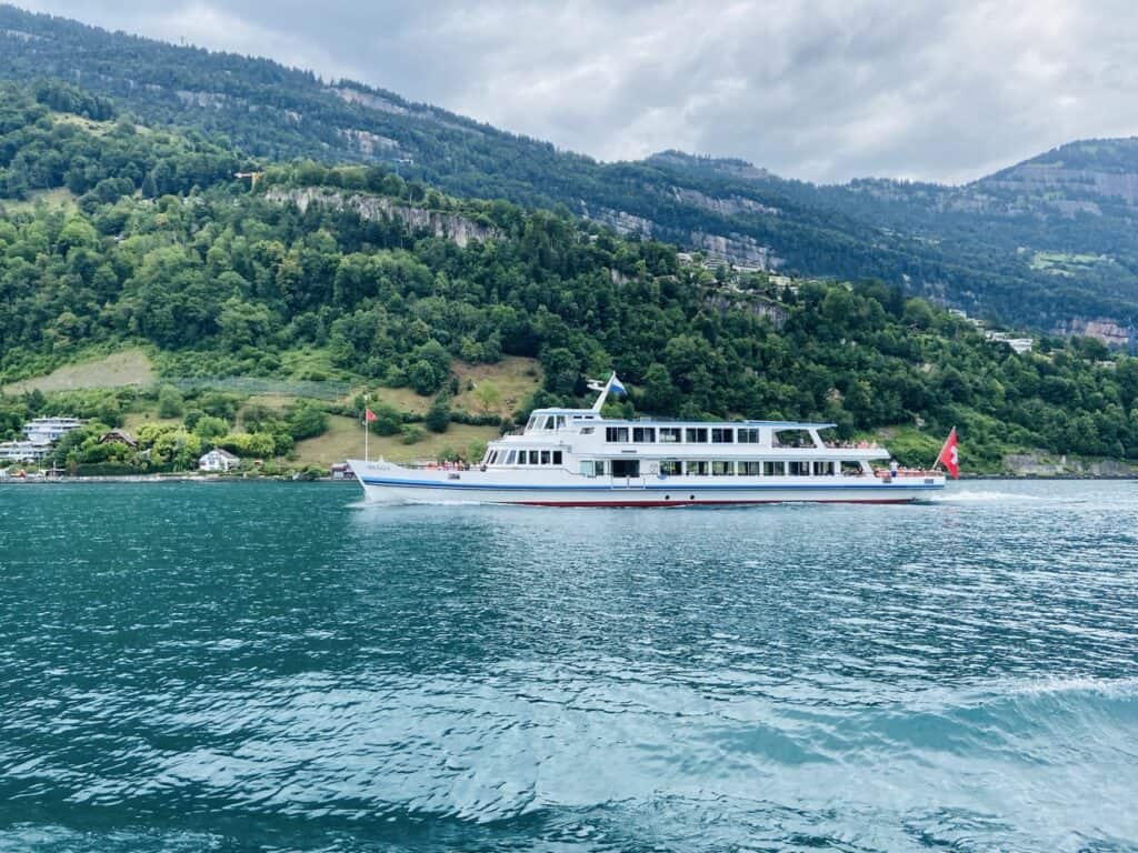 Passenger boat cruising across a scenic Swiss lake.