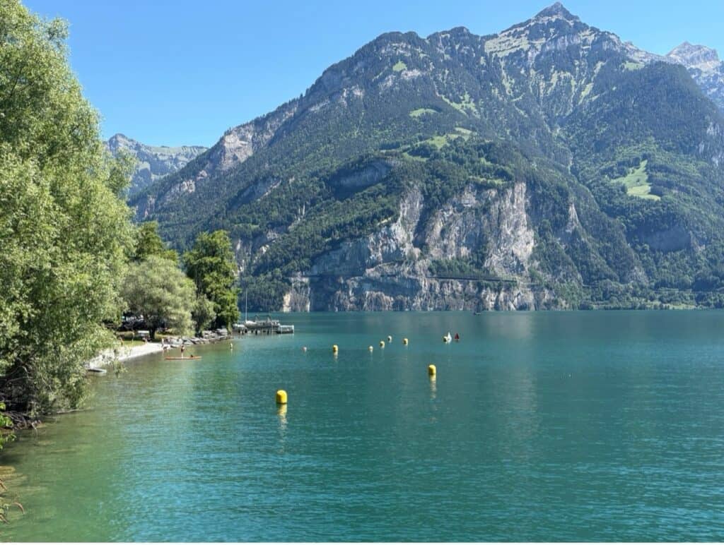 Isleten Beach at the turquoise blue Lake Lucerne surrounded by mountains. 