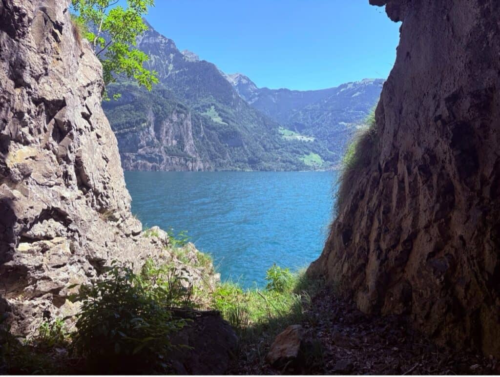 Looking out from the dark interior of a stone tunnel onto the bright, sparkling blue waters of Lake Lucerne.