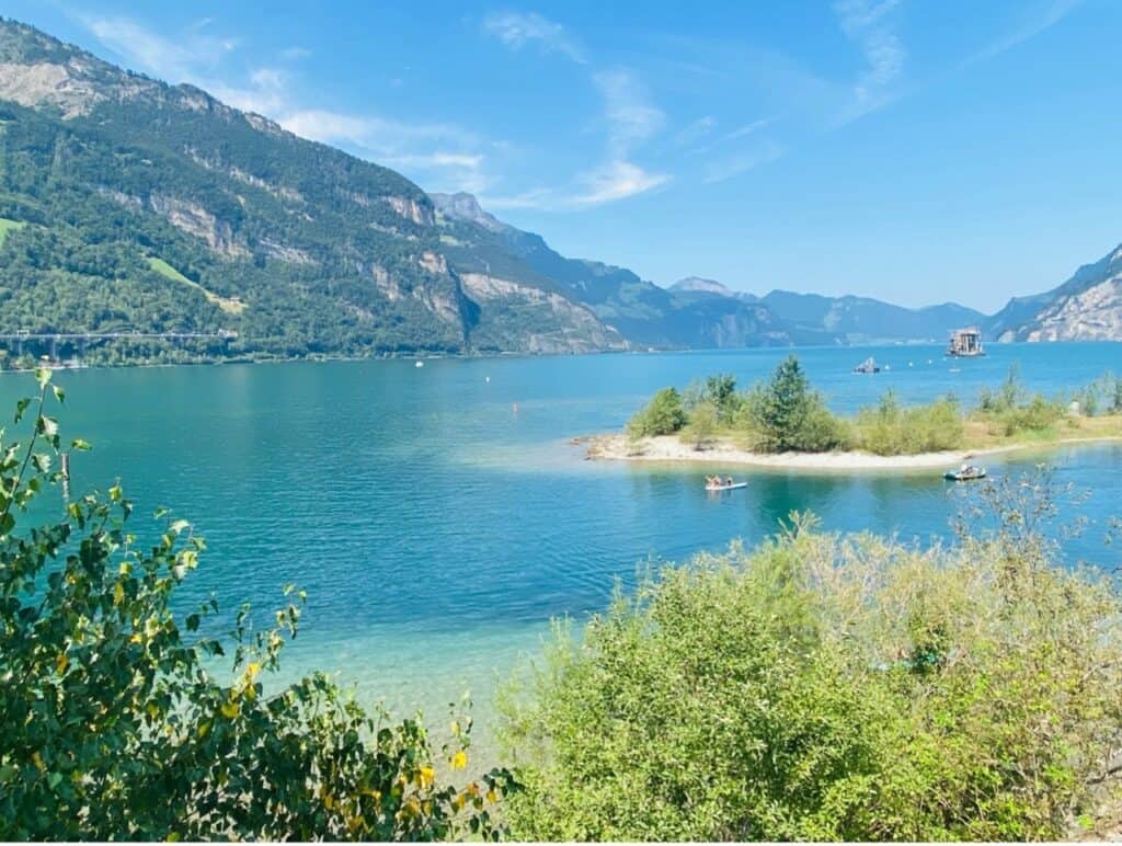 The Lorelei bathing islands in the Urnersee of Lake Lucerne, showing deep blue water and a shallow shoreline resembling the Caribbean.