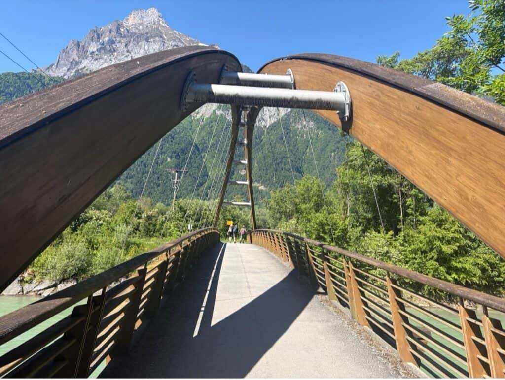 Suspension bridge over Reuss river with mountain in background. 