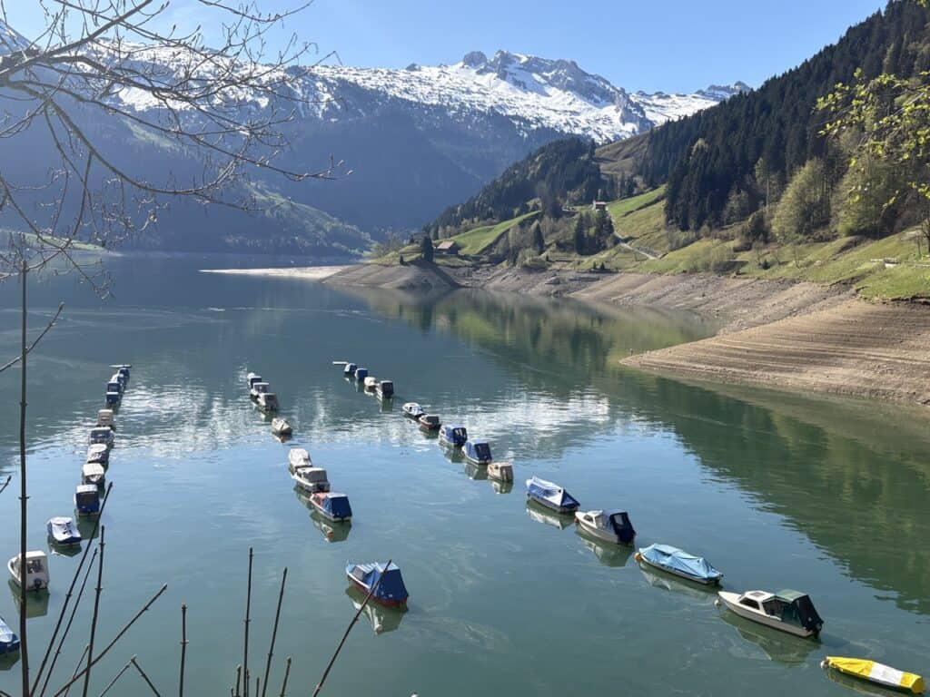 View across Wägitalersee with rows of small boats and snow-capped peaks