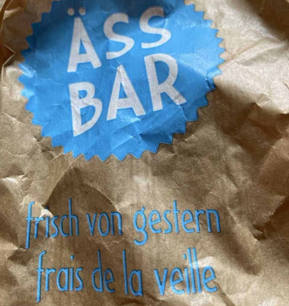 Paper bag with the blue Ässbar logo, a Swiss bakery chain selling unsold bread and pastries at discounted prices.