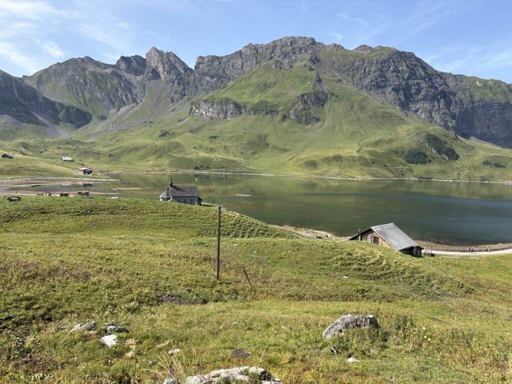 Scenic Melchsee lake with its picturesque lakeside chapel, surrounded by beautiful alpine mountains on the Four Lakes Hike Switzerland.