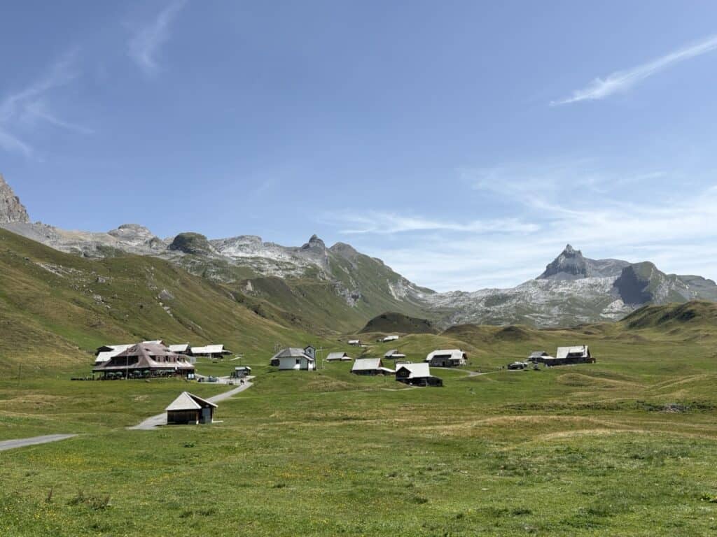 Scenic view of Tannalp along the Four Lakes Hike Switzerland, with the traditional Berggasthaus, charming alpine houses and a small chapel surrounded by beautiful mountain scenery.
