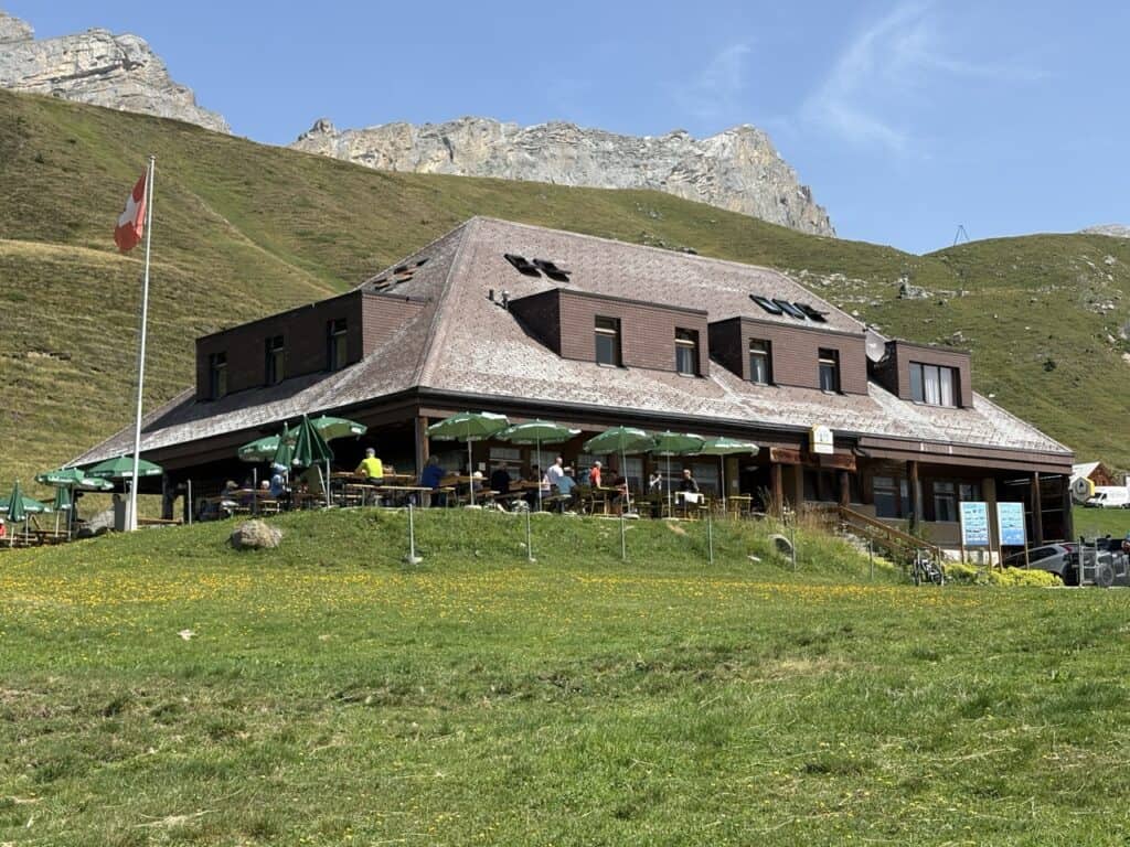 Bergrestaurant Tannalp surrounded by alpine meadows and mountain scenery, a lovely place to stop for refreshments on the Four Lakes Hike Switzerland. 