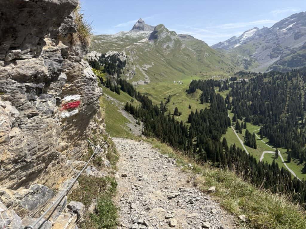 Rocky alpine hiking trail with a safety rope along the route towards Engstlenalp, one of the more rugged sections of the Four Lakes Hike Switzerland.